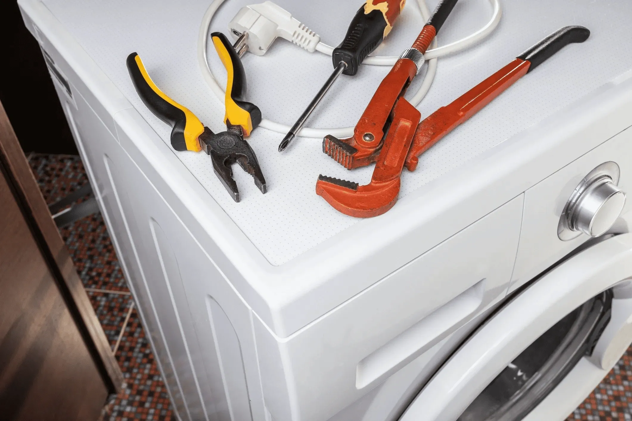Tools for repairing appliances are lying on the washing machine.