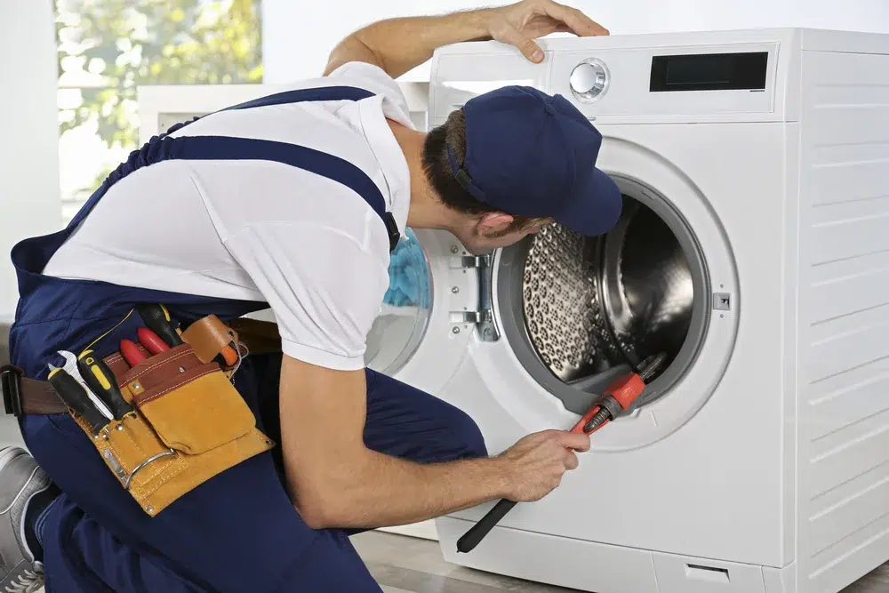 A home appliance repairman is fixing a washing machine.