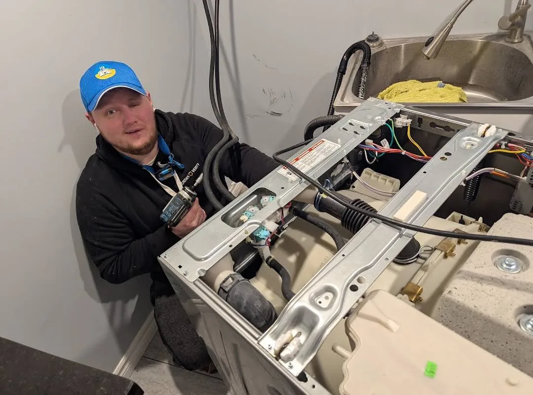 A home appliance repairman is fix-appliance.caing a washing machine.
