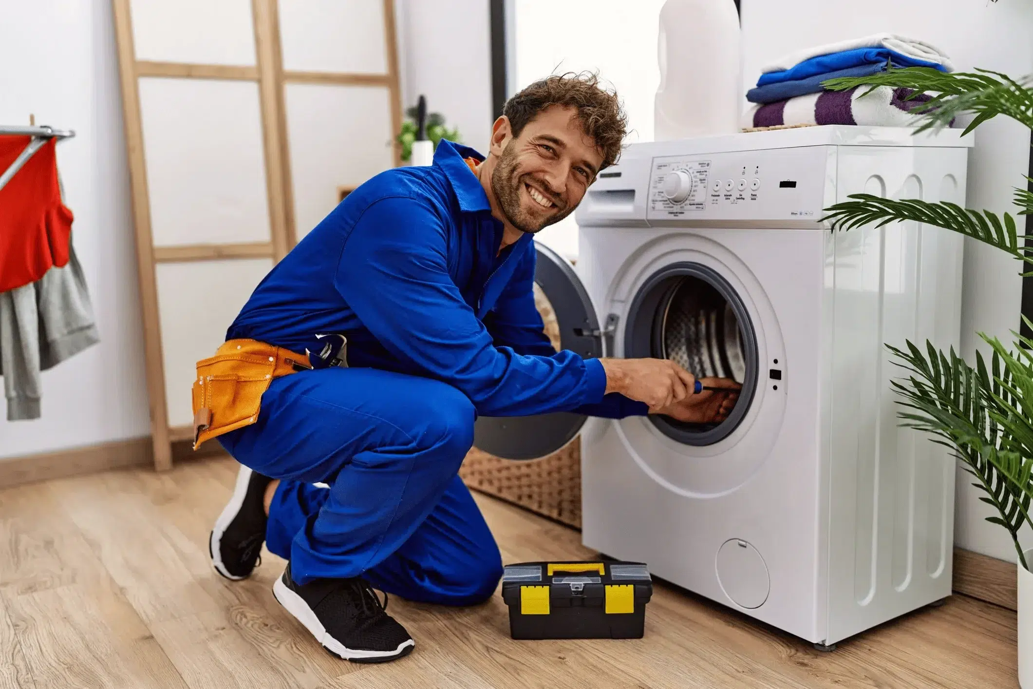 A household appliance repairman repairs a Frigidaire washing machine.