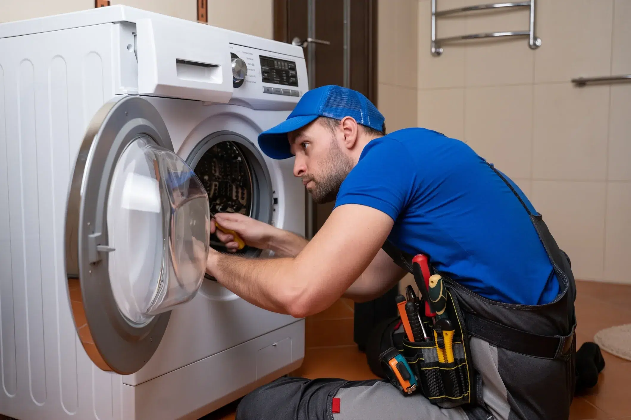 A household appliance repairman repairs a washing machine in Cambridge