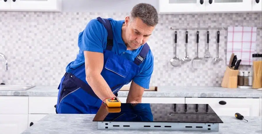 A household appliance repairman repairs an electric hob.
