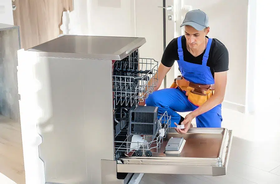 A home appliance repairman in Simcoe is repairing a dishwasher.