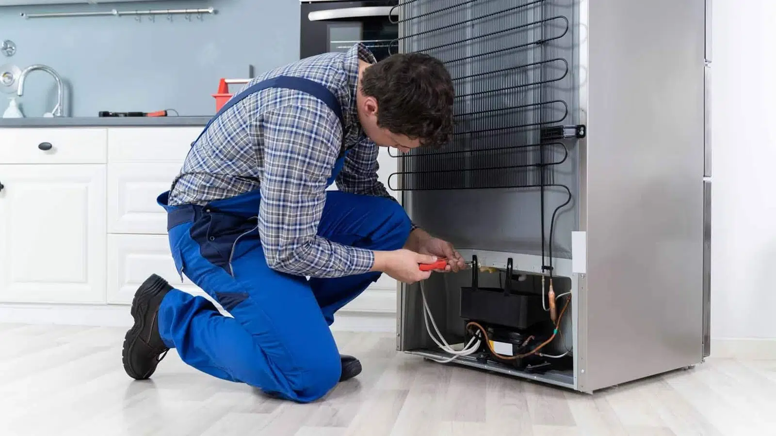 A refrigerator repair technician enters into a refrigerator repair